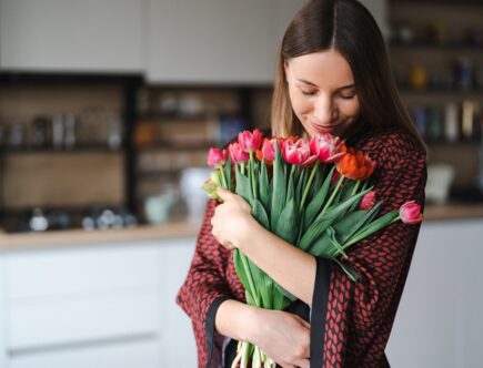 Kobieta cieszy się bukietem tulipanów w kuchni